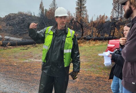 A traffic volunteer talking with other volunteers about the damage caused by the fire, gesturing to the debris.